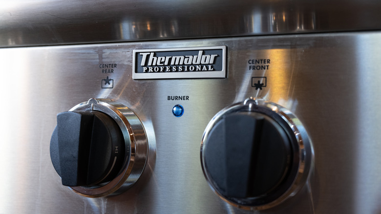 A close-up of an embossed Thermador logo aove two burner knobs