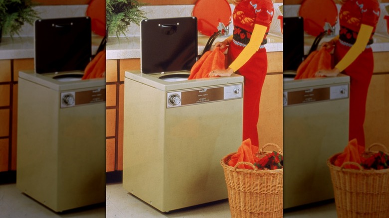 Woman using a vintage 1970s portable washing machine in the color almond in the kitchen