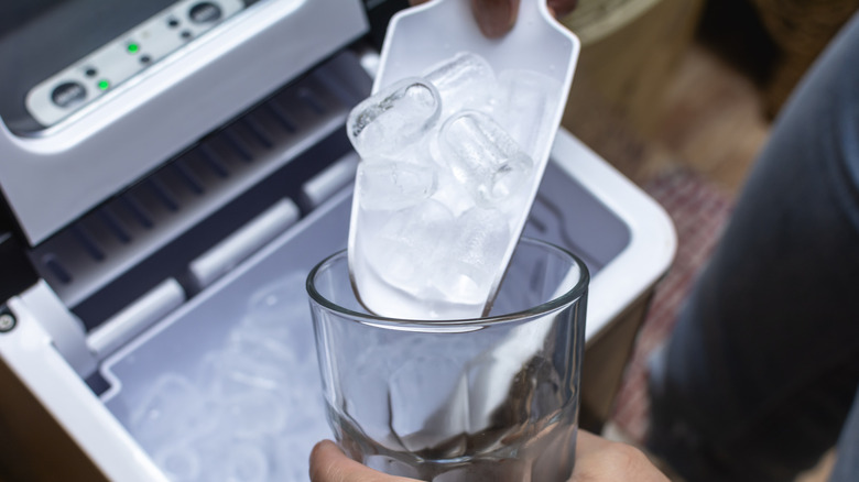 Scooping ice from a countertop ice maker into a cup
