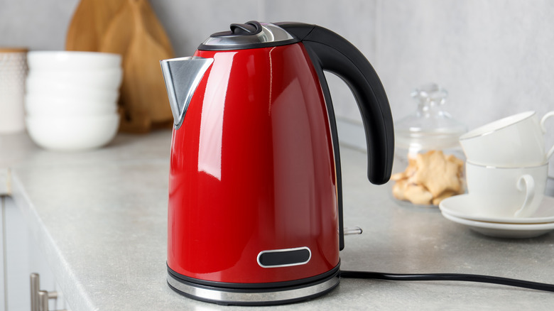 A red electric kettle in a grayish-white kitchen