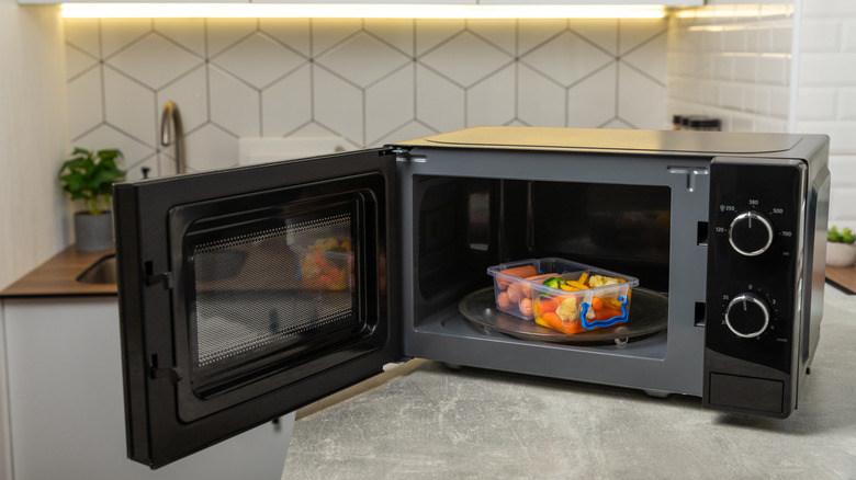 A black microwave on a countertop with food inside