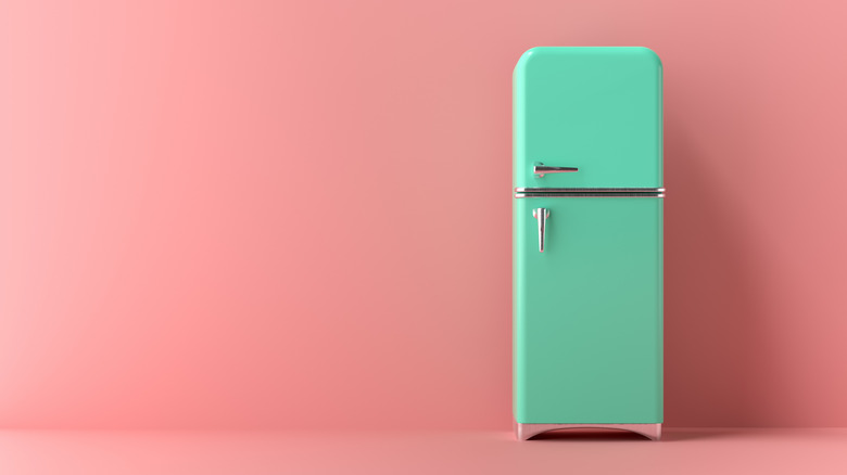 A vintage-style turquoise refrigerator in a pink room