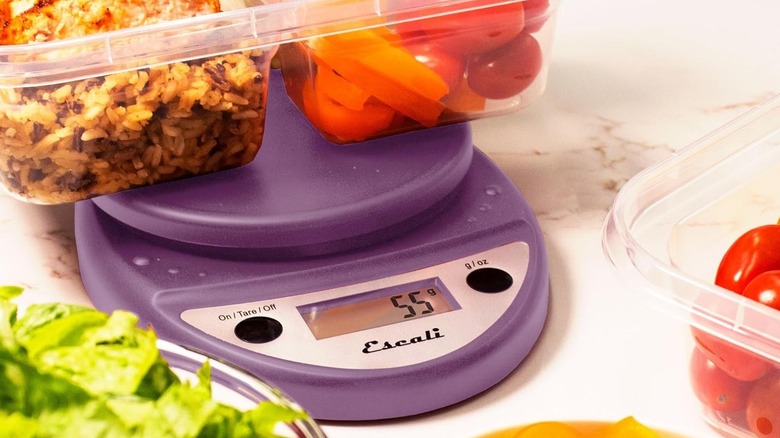 A purple digital food scale with a tupperware of rice and vegetable on top