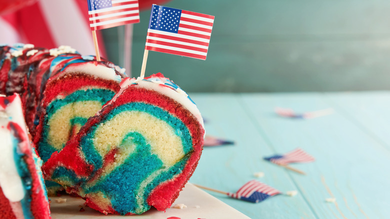 Sliced pound cake with red and blue swirls inside and topped with American flag toothpicks