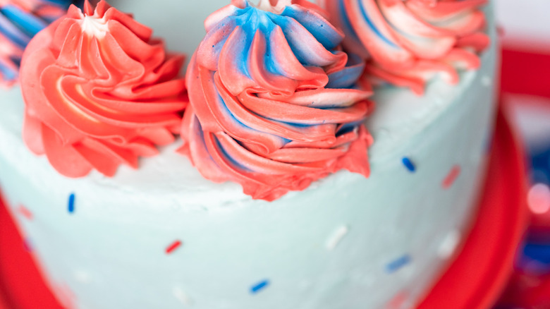 Red, white, and blue frosting rosettes on white iced cake