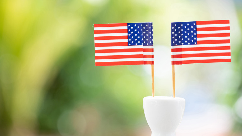 Two American flags on toothpicks stuck into white vessel