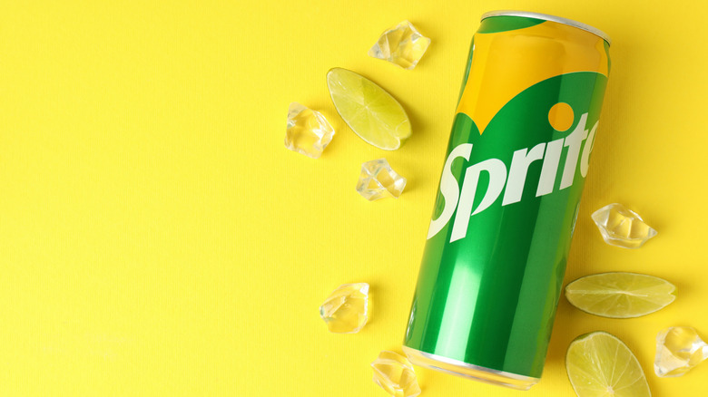 A can of Sprite on a yellow background with ice cubes and lime slices