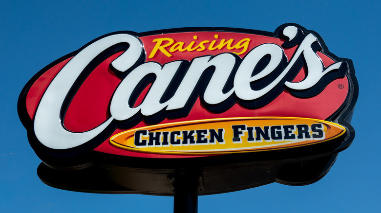 Raising Cane's Chicken Fingers sign against blue sky