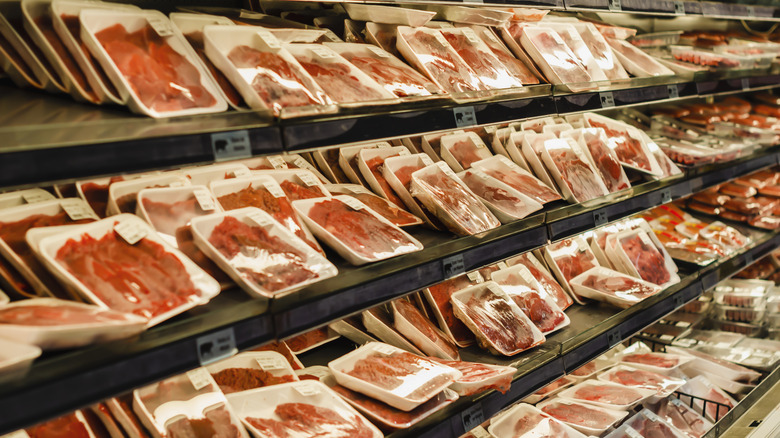 Packages of meat stacked in supermarket cooler