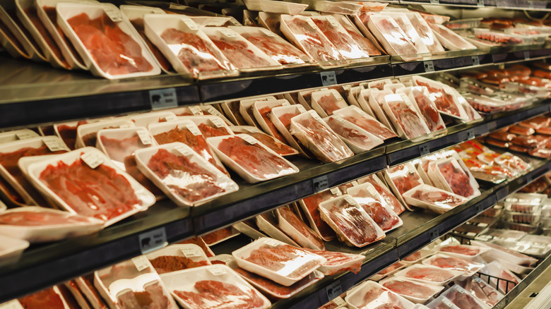 Packages of meat stacked in supermarket cooler
