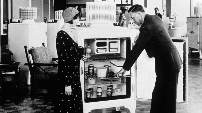 Salesman and woman standing in front of a GE Monitor-Top refreigerator