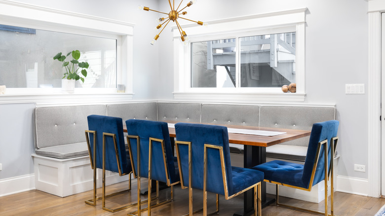 1960s inspired banquette seating in a kitchen with royal blue chairs and a gray dining bench.