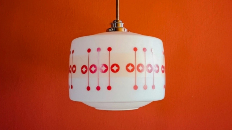 1960s kitchen milk glass pendant light with red imagery against a red background.