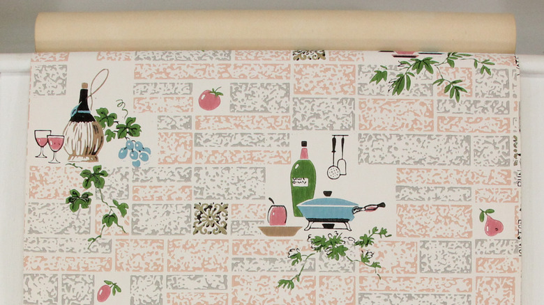 A roll of 1960s-style wallpaper with bottles of wine, oil, tomatoes, leaves, and a skillet, among other items.