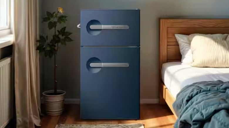 A dark blue, 2 door, vintage-style Frigidaire mini fridge in a bedroom.