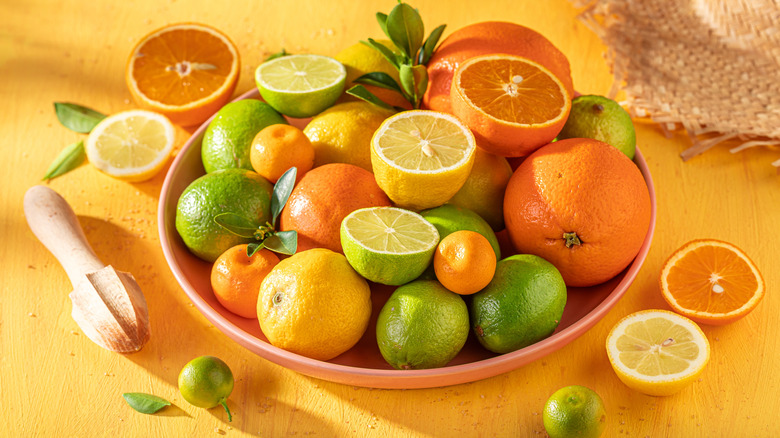 Bowl of citrus fruits including lemons, limes, and oranges with green garnish