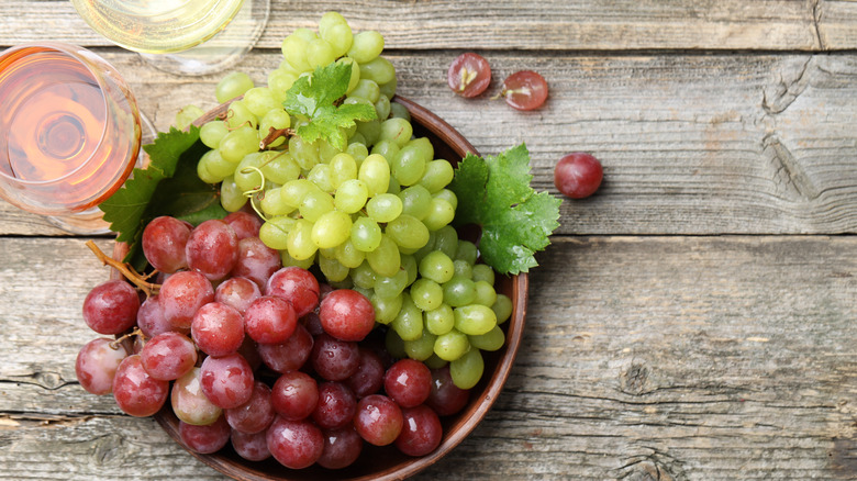 Bowl of red and green grapes next to two glasses of wine