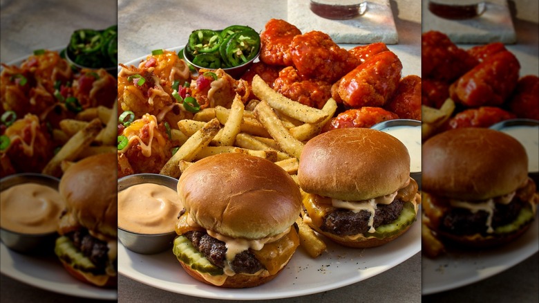 An appetizer sampler with sliders, fries, wings, and loaded potato skins