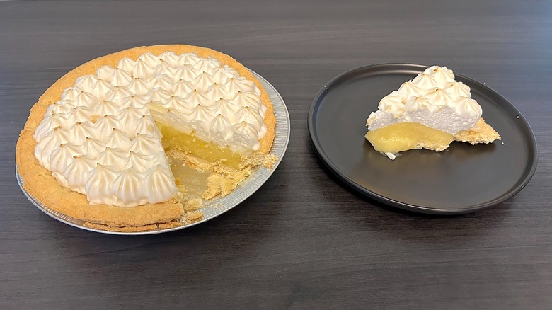 Marie Callender's lemon meringue pie with slice missing and the slice on a black plate