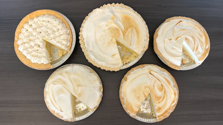 Five lemon meringue pies with slices missing