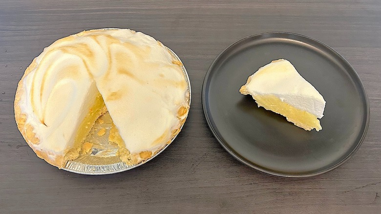 Sugar free lemon meringue pie with a slice removed and the slice on a black plate