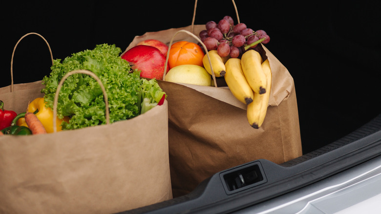 Groceries in brown paper bags inside a car trunk
