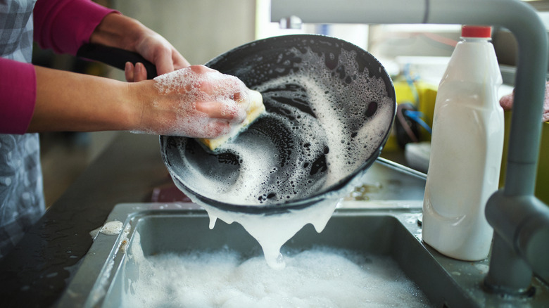 Person scrubbing a pan with soapy water