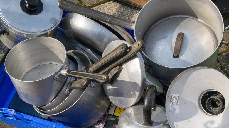 Crate containing old pots and pans with lids