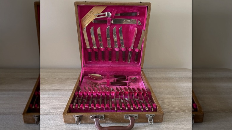 Open, velvet-lined box of gold-plated dessert forks, knives, and spoons