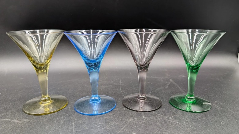 Four short, stemmed cordial glasses in yellow, blue, gray, and green colors
