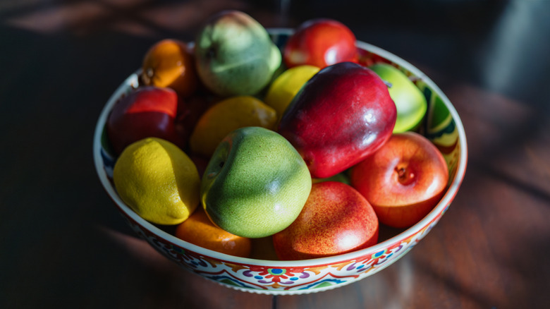 Bowl of decorative fruits, including apples, pears, and oranges