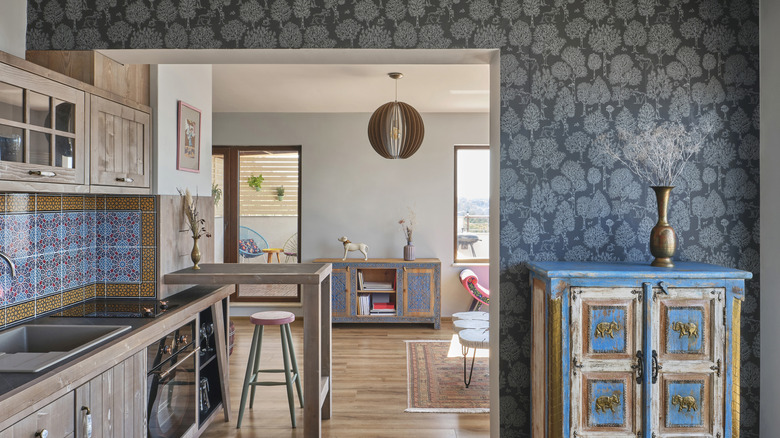 A kitchen wall covered in dark blue wallpaper with tree print patterns