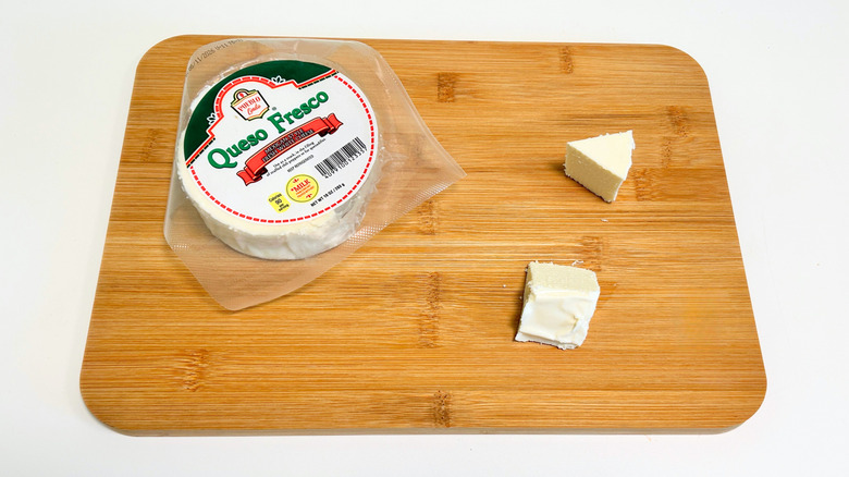 Pieces of cheese on a cutting board next to a package of Pueblo Lindo Queso Fresco