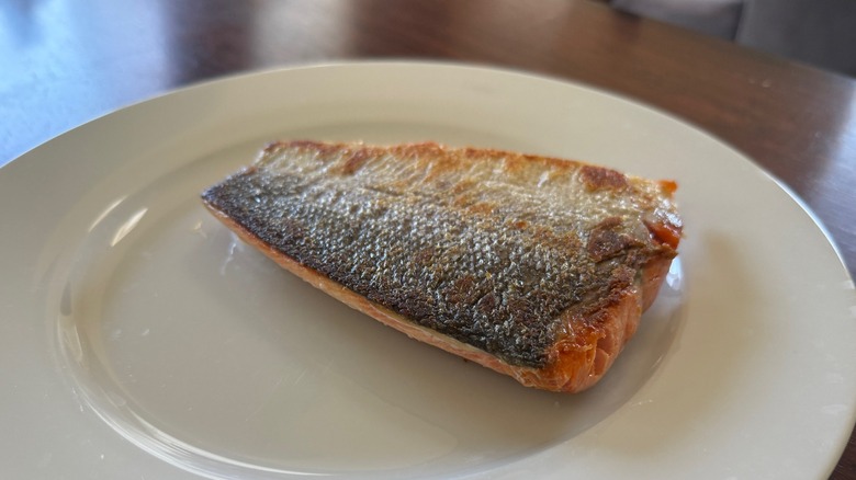 A piece of cooked sockeye salmon skin-side up on a white plate