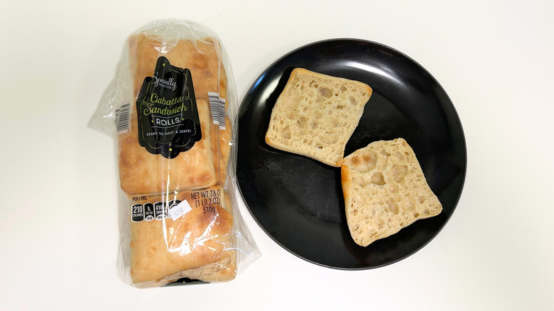 A bag of Specially Selected Ciabatta Sandwich Rolls next to a black plate with a split ciabatta roll