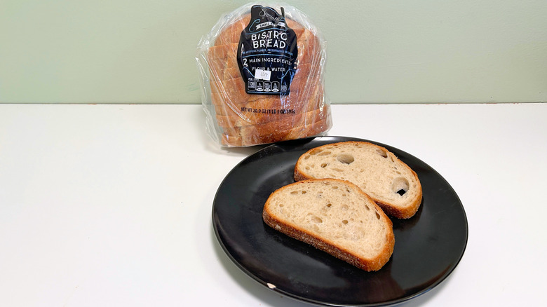 A bag of Specially Selected Small Batch Bistro Bread next to a black plate with bread slices