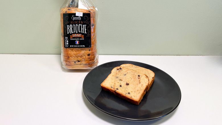 A bag of Specially Selected Sliced Chocolate Chip Brioche Loaf next to a black plate with bread slices