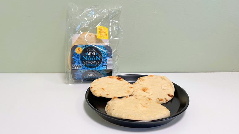 A bag of Specially Selected Mini Naan Flatbread next to a black plate of flatbread