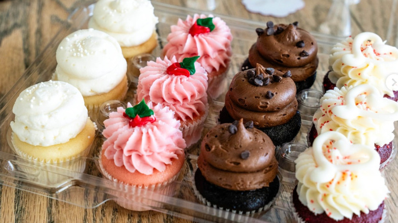 A zoomed in photo of different photos of Gigi's Cupcakes in a plastic container