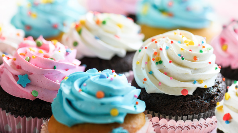 A closeup photo of pink, white, and blue cupcakes with sprinkles