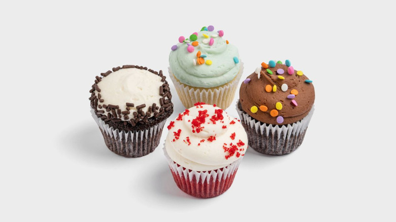 Four different colored cupcakes from SusieCakes against a white backdrop