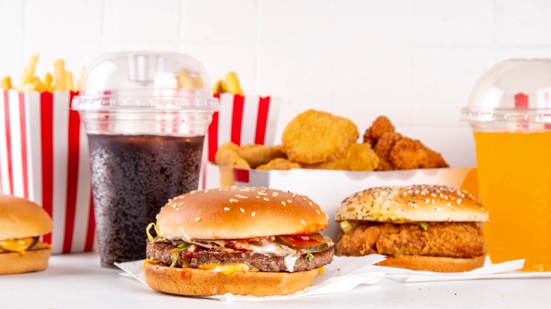 A fast food spread featuring sodas, French fries, burgers, and fried chicken