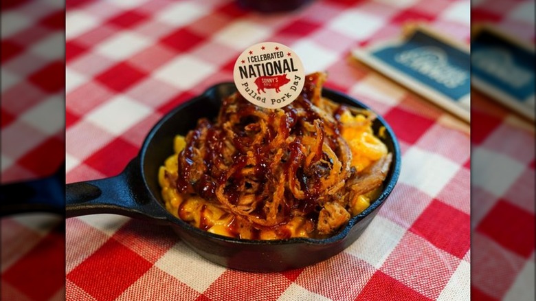 Cast iron skillet with puled pork mac and cheese. A sign says "I celebrated National Pulled Pork Day."