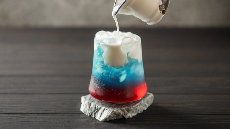 Blue and red soda in a glass with milk poured in