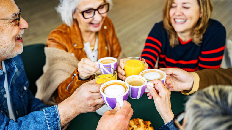 A group of baby boomers cheers at a coffee shop