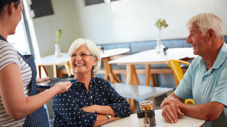 A server waiting on a senior couple at a cafe