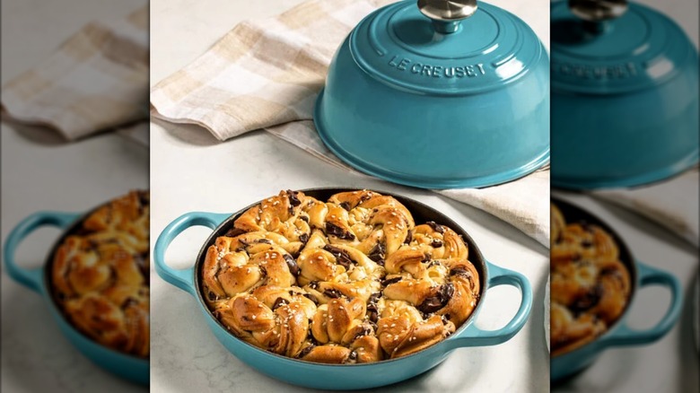 A Le Creuset bread oven in Caribbean, a light blue, opened to reveal bread inside