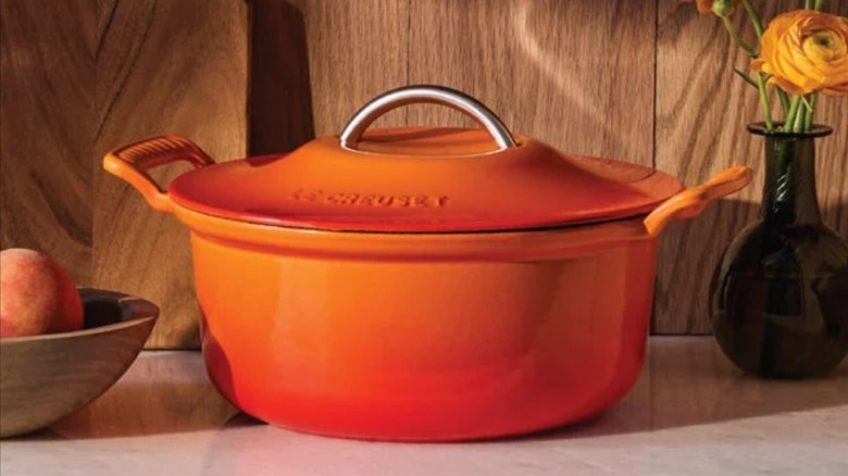 A Le Creuset Modern Heritage Oval Dutch Oven in Flame, a vibrant orange color