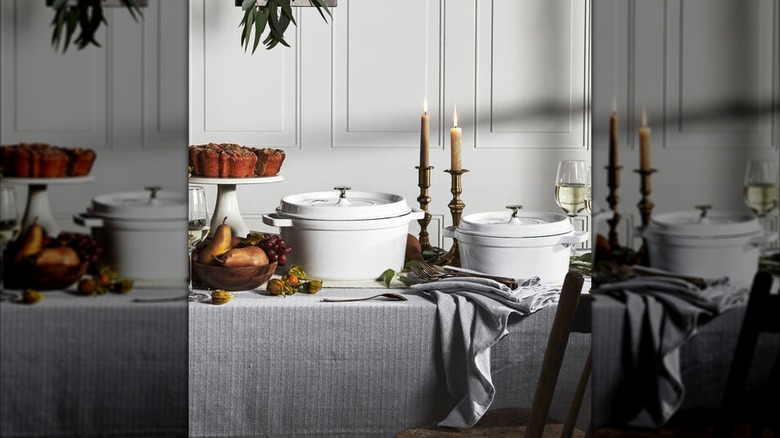 Two Staub Dutch ovens in white on a table in a mostly white dining room