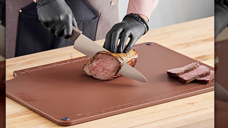 man cutting cooked meat on a brown cutting board
